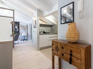 Eine moderne Küche mit weißen Schränken, einem Holztischchen und einer großen gewebten Vase.