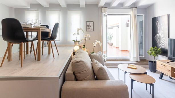 Een moderne woonkamer met een bank, eettafel, stoelen en een televisie.