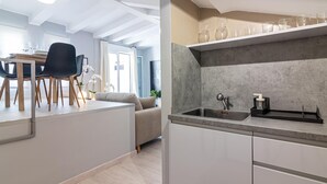 Een moderne keuken met een inbouwspoelbak, een eethoek met tafel en stoelen, en een woonruimte met een bank.