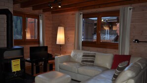 A cozy living room with a sofa, ottoman, television, and a fireplace.