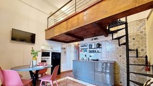 A compact kitchen with a wooden ceiling, a dining area with pink chairs, and a tiled backsplash. - 4bnb - Cozy Vatican Loft With Terrace (Rome)