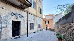 A narrow cobblestone alley with buildings on either side, featuring arched doorways and traditional shutters. - 4bnb - Cozy Vatican Loft With Terrace (Rome)
