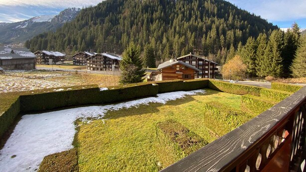 Un refugio de montaña con varias cabañas de madera, un terreno cubierto de nieve y un paisaje boscoso.