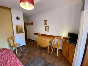 Une petite pièce agréable, dotée d’un lit, d’une table en bois avec des chaises, d’un téléviseur et d’un miroir.