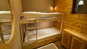 Habitación con literas, paredes de madera y una ventana pequeña.