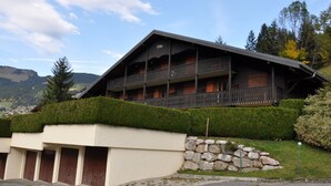 Un edificio de estilo chalet con techo pronunciado, varios balcones y base de piedra.