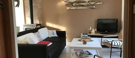 A living room with a black sofa, a white coffee table, a television, and a fireplace.