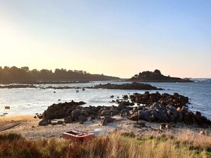 A rocky beach with boats and a small boat in the foreground.