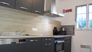 A modern kitchen with grey cabinets, a stainless steel dishwasher, a built-in oven, and a coffee maker.