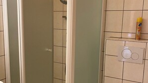 Et badeværelse med bruser, toilet og et panel til styring af installationer.