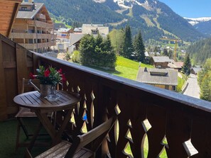A wooden balcony with a table and chairs, overlooking a mountainous village with houses and greenery. - Spacious apartment with mezzanine near Châtel center (Châtel)