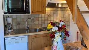 Et køkken med en Bosch opvaskemaskine, kaffemaskine, vask og en vase med blomster.