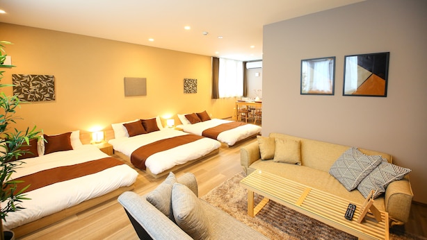 A hotel room with two beds, a sofa, a coffee table, and a dining area. - PrimeRoomBeppu Hamawaki (Beppu)