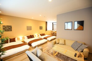 A hotel room with two beds, a sofa, a coffee table, and a dining area. - PrimeRoomBeppu Hamawaki (Beppu)