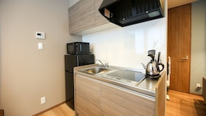 A compact kitchen with a built-in microwave, a sink, and a kettle on the countertop. - PrimeRoomBeppu Hamawaki (Beppu)