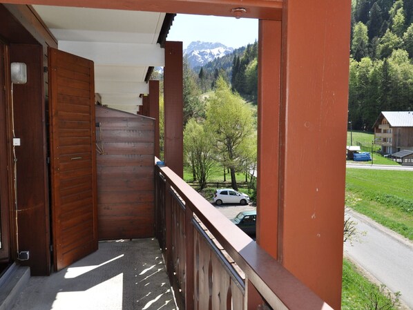 A wooden balcony with a view of a mountain and a road with cars.