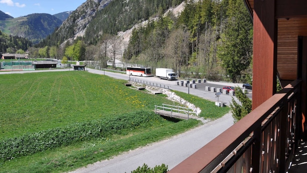 Vista de la montaña con carretera, autobús y edificio con balcón.