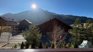 Blick auf einen Berg mit strahlender Sonne hinter der Spitze, umgeben von Wohnhäusern und Bäumen.