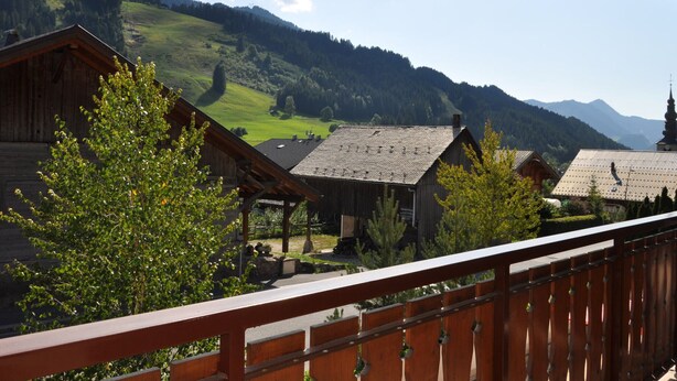 Eine Holzhütte mit einem Balkon mit Blick auf eine Berglandschaft.