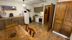 Una cocina compacta con muebles de madera, una mesa de comedor y un refrigerador.