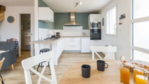Eine moderne Küche mit weißen Schränken, einem Holztisch und einem Frühstücksarrangement mit Tassen und Gläsern.