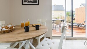 Ein Essbereich mit einem Holztisch, weißen Stühlen und einer Glastür zu einer Außenveranda.