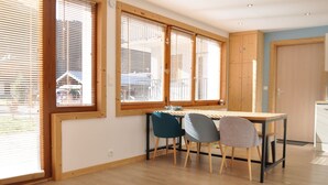 Una habitación luminosa con ventanas amplias, una mesa de madera y sillas.