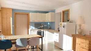 Una cocina moderna con armarios blancos, una mesa de madera y dos sillas.