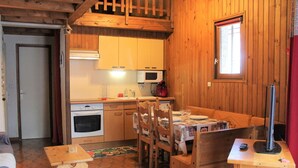 Una cabana de fusta acollidora amb cuina, menjador i taula petita amb cadires.