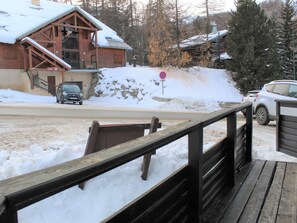 A wooden cabin with a snow-covered roof, a wooden deck, and a no parking sign in the background. - Mezzanine Apartment Sleeps 7 in Central Vars Les Claux (Vars)