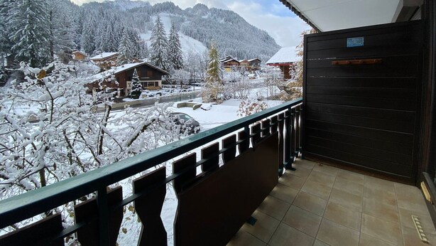 A balcony with a view of a snow-covered mountain landscape, including several buildings and a road. - Cozy studio with balcony and WIFI near Linga slopes (Châtel)