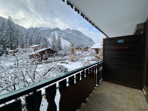 A balcony with a view of a snow-covered mountain landscape, including several buildings and a road.