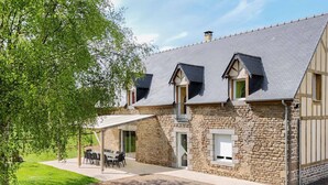 A stone building with a sloped roof, a covered patio with outdoor furniture, and a grassy area. - Restored Traditional House - Pets Allowed, WIFI, Enclosed Garden (Landisacq)