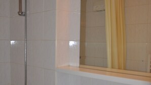 A bathroom with white tiles, a shower with a glass door, and a mirror with a yellow shower curtain. - Cozy apartment near slopes with balcony and parking (Châtel)
