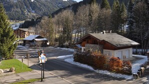 A mountain lodge with a wooden exterior, a small porch, and a view of a snow-covered mountain. - Cozy apartment near slopes with balcony and parking (Châtel)