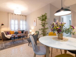 Un salon moderne avec un canapé, une table à manger et une grande plante en pot.