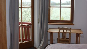 A bedroom with a bed, a desk, and a window overlooking a body of water. - Place in the sun (Gräfenberg)