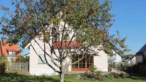 A house with a red balcony, surrounded by a well-maintained garden and a clear blue sky. - Place in the sun (Gräfenberg)