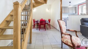 Un intérieur moderne avec un escalier en colimaçon en bois, un coin repas avec des chaises rouges et un canapé gris.