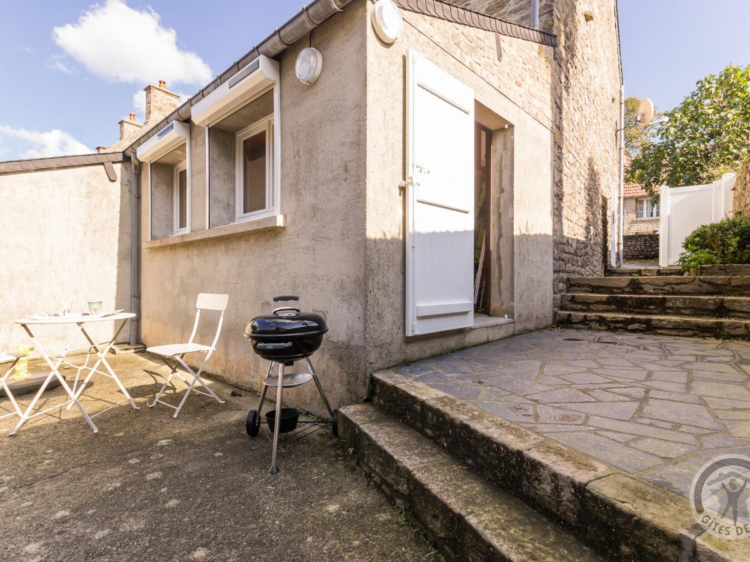 A stone building with a barbecue grill, outdoor seating, and a stone staircase.
