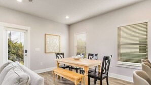 A dining area with a wooden table and chairs, a bench, and a framed picture on the wall.