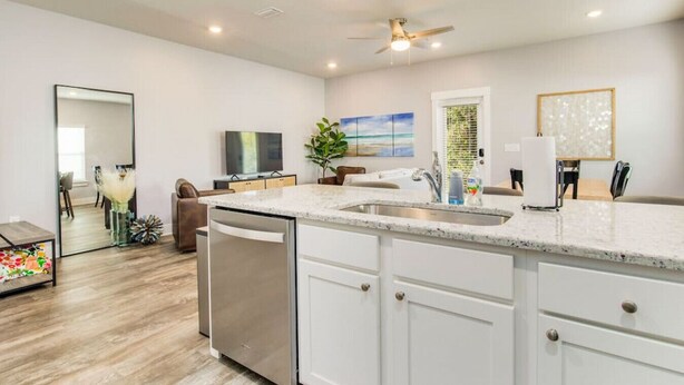 A modern kitchen with white cabinets, a granite countertop, and a built-in dishwasher.