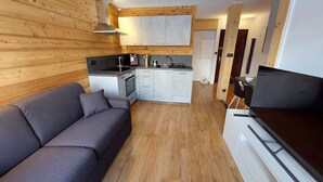 Un espacio habitable compacto con kitchenette, un sofá y un televisor.