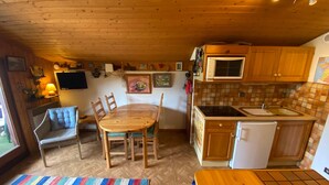 Une cuisine chaleureuse avec des meubles en bois, une table à manger et un petit réfrigérateur.