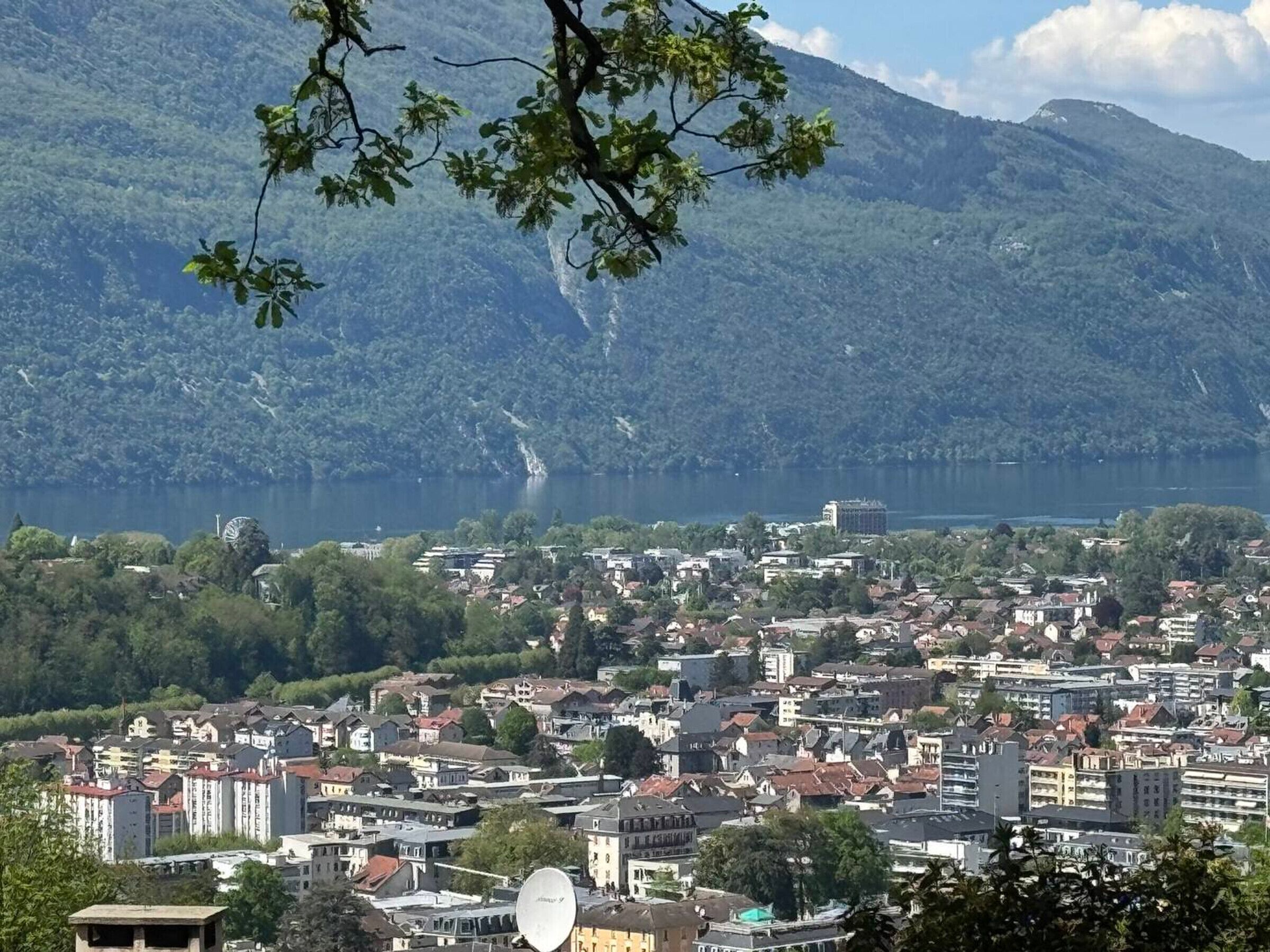 Une ville bordée d’un lac, avec des montagnes en arrière-plan.