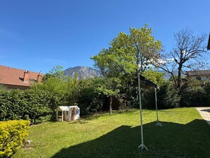 A backyard with a small playhouse, a tree, and a mountain in the background.