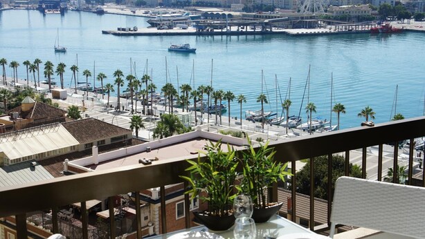 Ein Balkon mit Essplatz, Blick auf eine Marina mit Booten und ein Riesenrad in der Ferne.