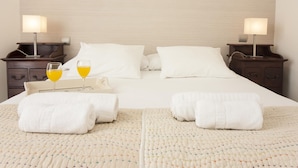 Ein Hotelzimmer mit einem Bett, zwei Nachttischen, einer Lampe und einem Tablett mit zwei Gläsern Orangensaft sowie zwei aufgerollten Handtüchern.