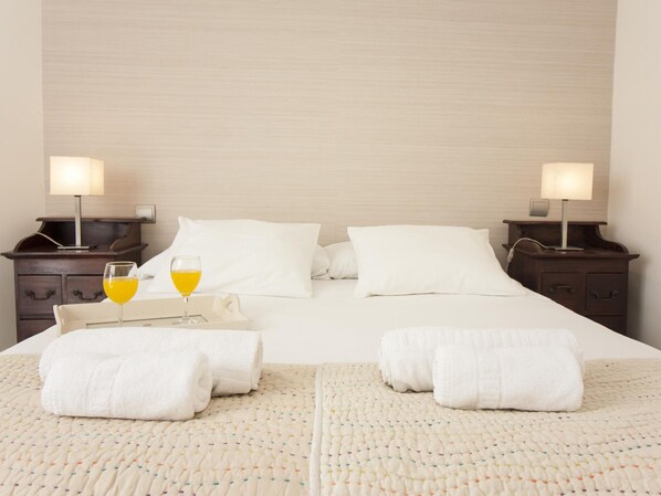 Hotelkamer met een bed, twee nachtkastjes, een lamp, een dienblad met twee glazen sinaasappelsap en twee opgerolde handdoeken.
