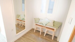 Una habitación con un banco de madera, un espejo grande y una ventana con persianas.
